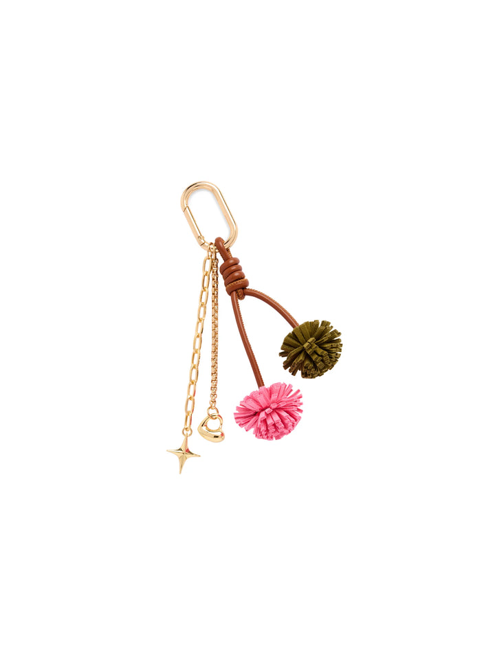 A gold-tone keychain or bag charm featuring a carabiner clip, a short chain with a star and small charm, and two hanging cord loops with pom-pom details in pink and olive green.