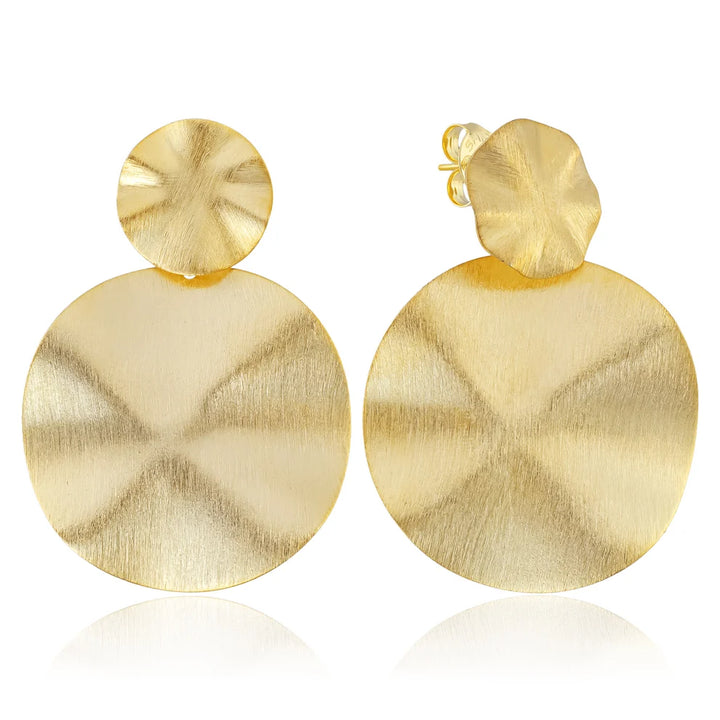 A pair of gold drop earrings with a textured circular disc and a smaller textured flower-like top, shown on a white background with a soft reflection below.