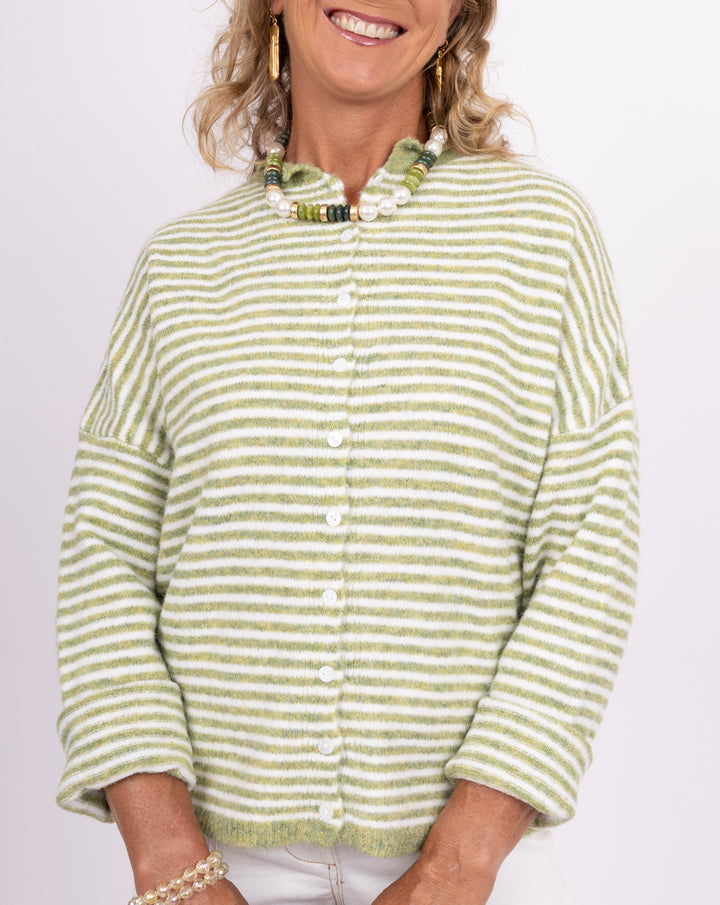 A woman wearing a fuzzy knit cardigan with light green and white horizontal stripes, featuring a scalloped collar and white buttons down the front.