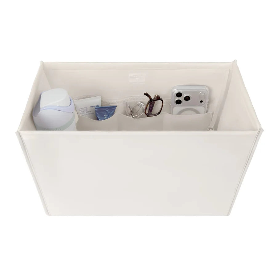 An off-white fabric organizer box with multiple interior pockets holding various small items, shown on a plain white background.