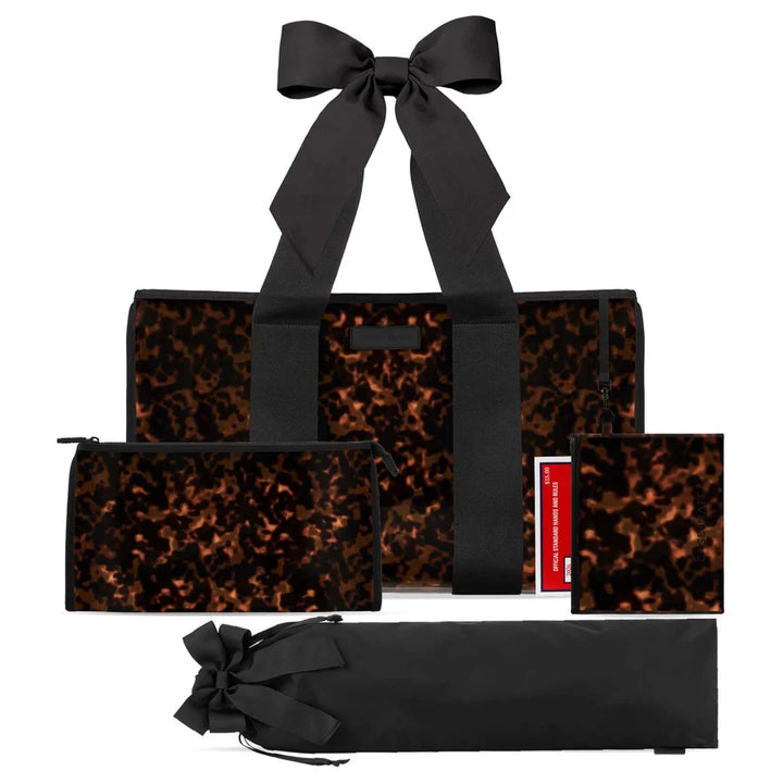A matching luggage and toiletry bag set in a black and brown abstract pattern, featuring a large tote bag with a black ribbon handle, a zippered pouch, a small square pouch, a folded black bag with a ribbon bow, and a red-and-white tag, all displayed on a white background.