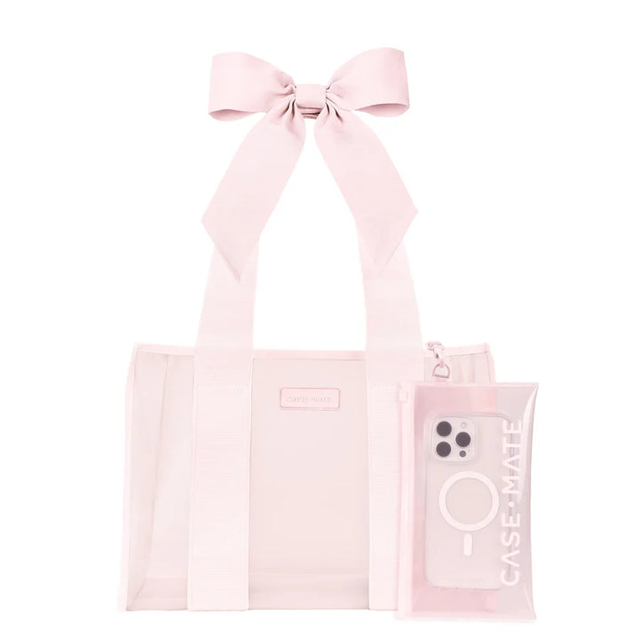 A light pink transparent tote bag with a large matching fabric bow on the handle, shown on a plain white background. A matching translucent phone case with a camera cutout and vertical &