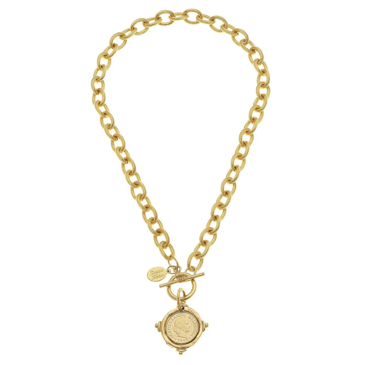 A gold coin toggle necklace with a textured chain and a coin pendant in the center, featuring the Swiss Confederation inscription.