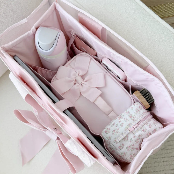 Pink beauty product set with a bow in an open box on a light background