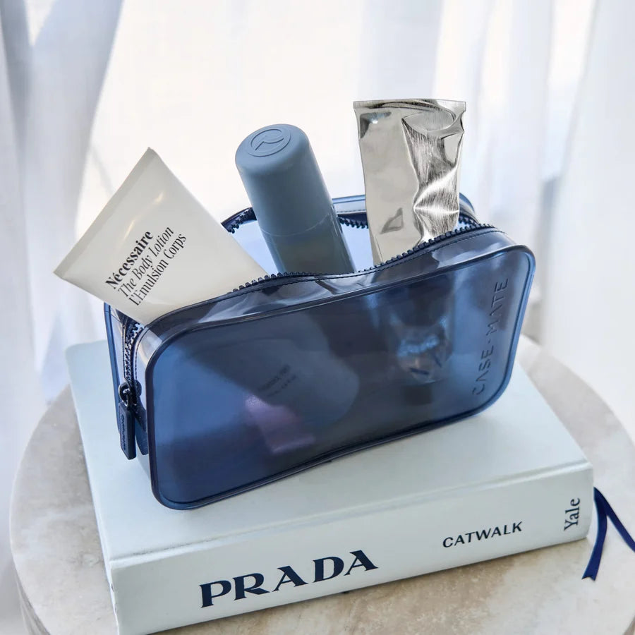 A translucent navy blue cosmetic pouch filled with toiletries, including a white tube labeled &