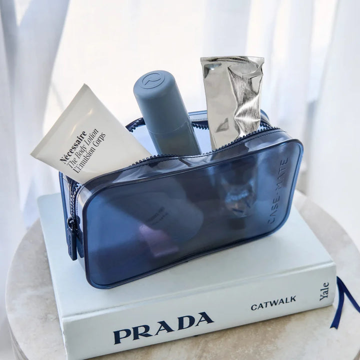 A translucent navy blue cosmetic pouch filled with toiletries, including a white tube labeled &