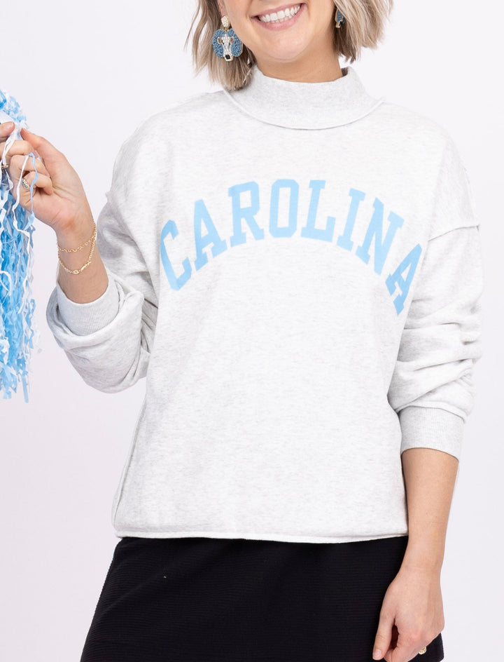 A woman modeling a white mock-neck sweatshirt with &