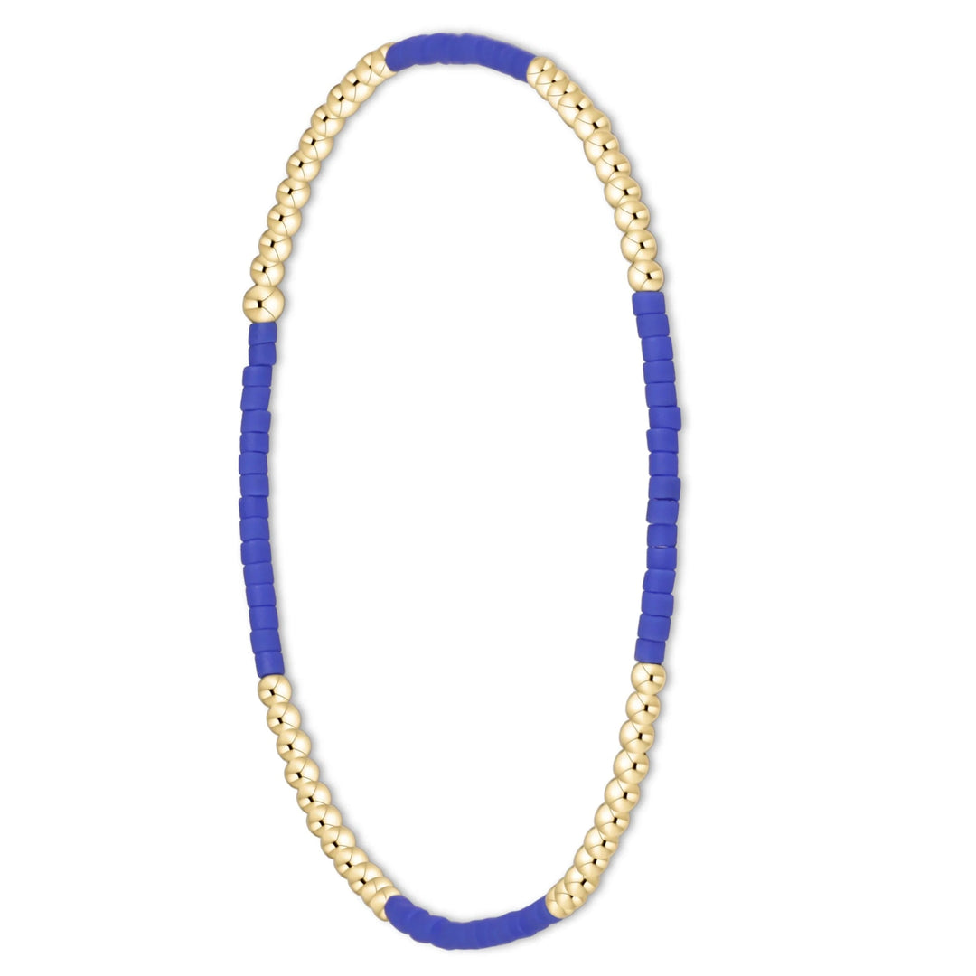 A beaded stretch bracelet featuring alternating sections of royal blue cylindrical beads and polished gold spherical beads, displayed on a clean white background.