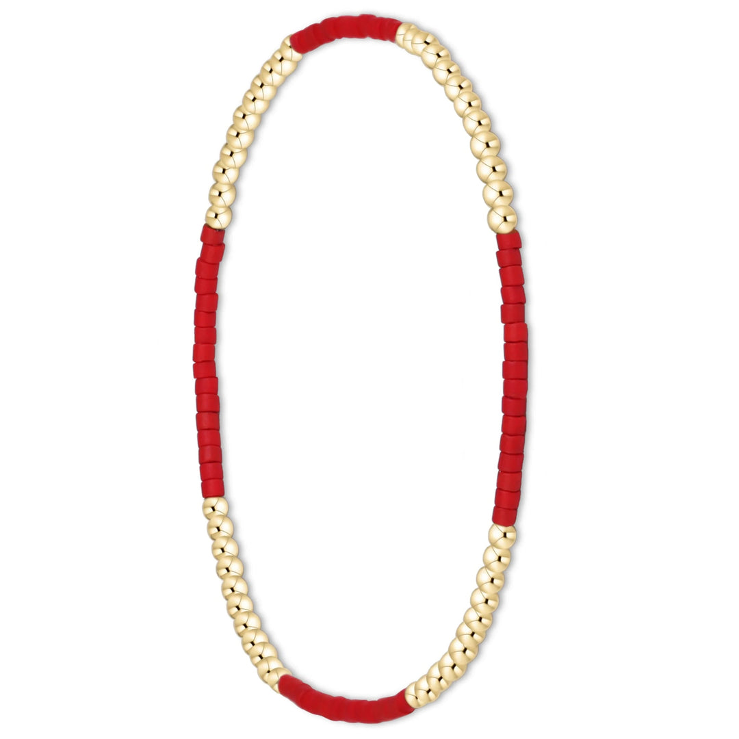 A beaded stretch bracelet featuring alternating sections of textured red cord and smooth gold-toned beads, displayed in a horizontal oval shape on a solid white background.