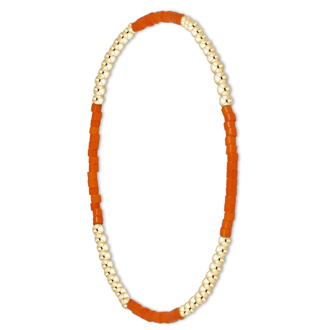 A beaded stretch bracelet featuring alternating strands of small metallic gold beads and rectangular orange beads, displayed on a clean white background.