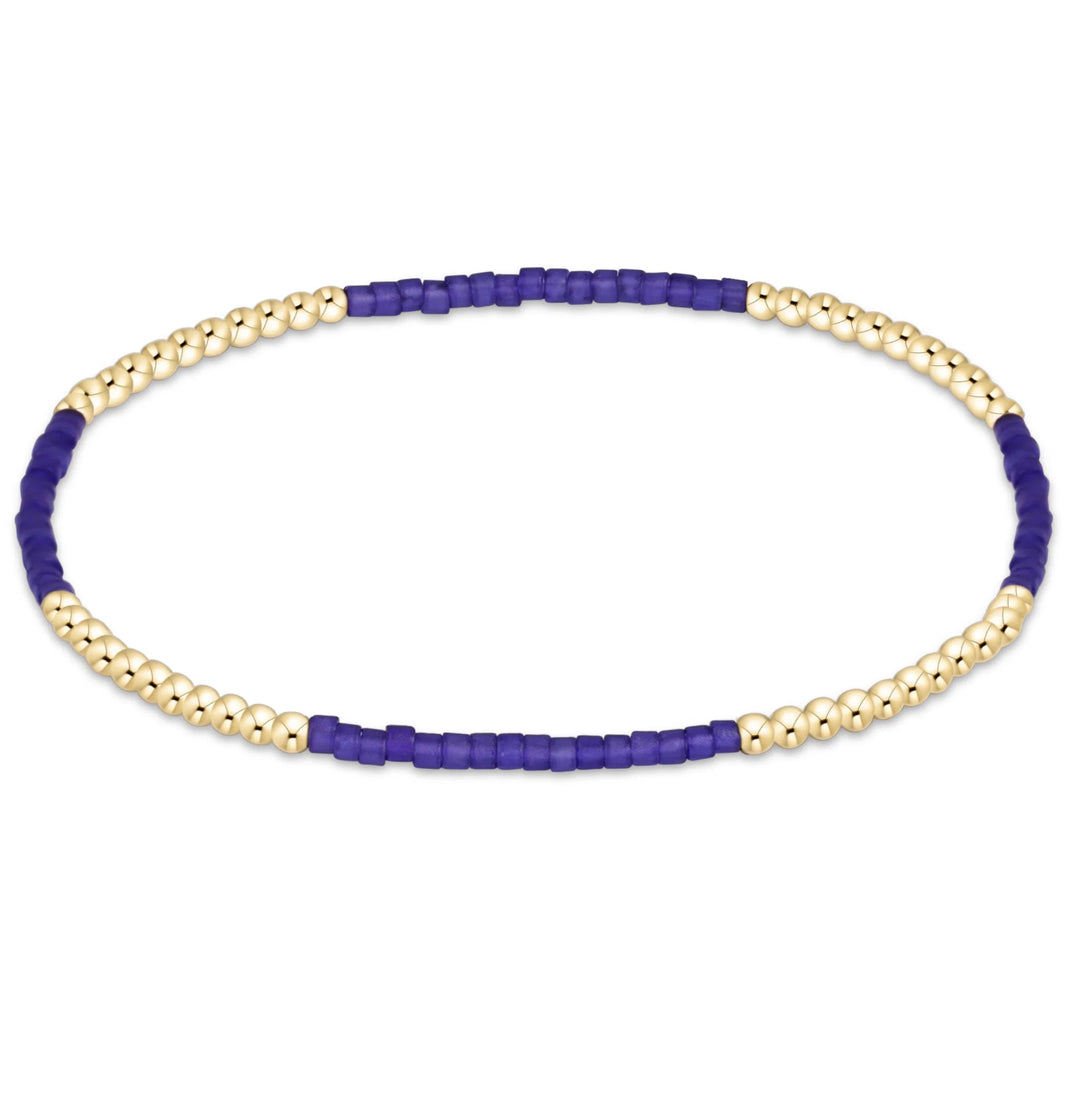A beaded stretch bracelet featuring alternating sections of smooth gold-toned beads and textured royal blue beads, displayed on a clean white background.
