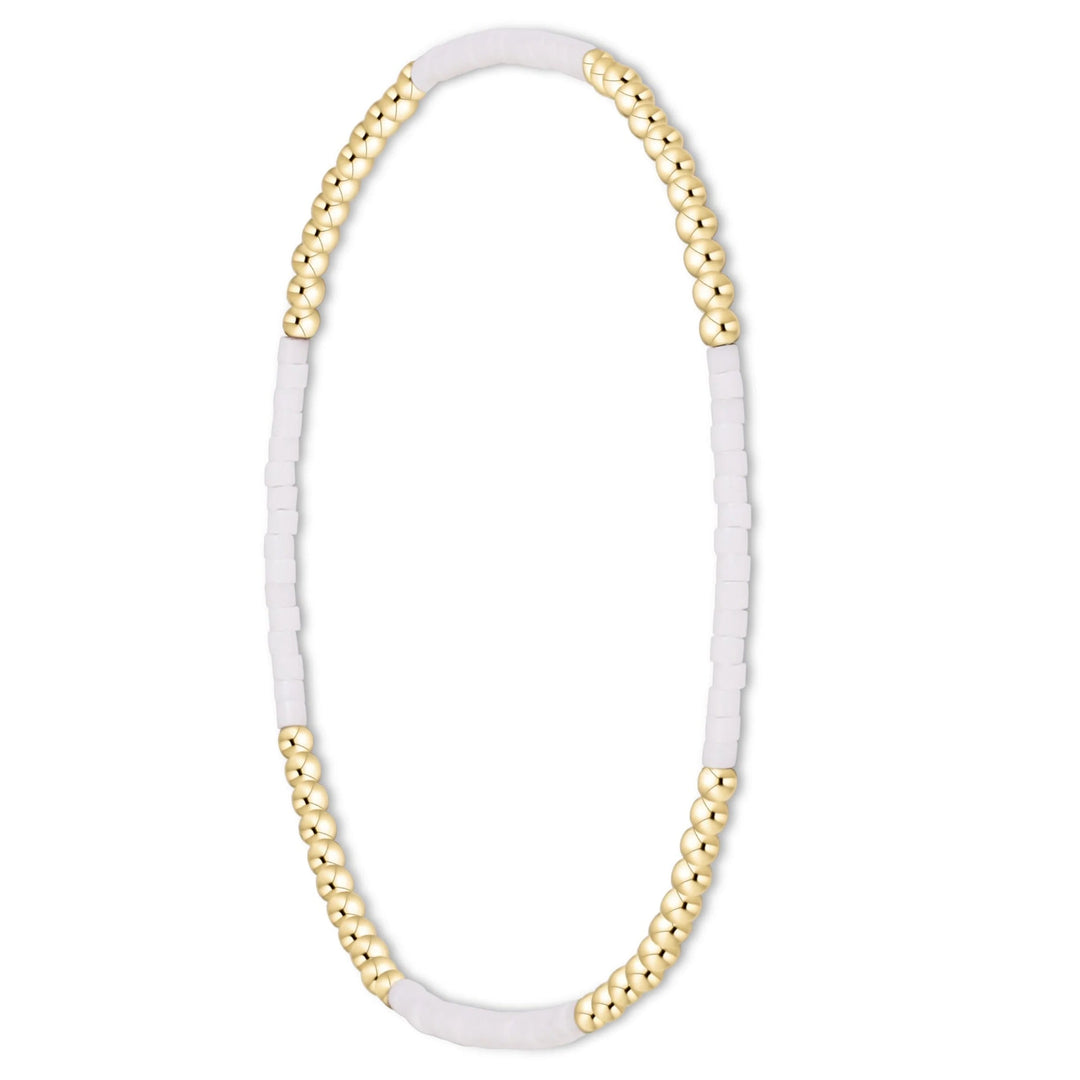 A delicate beaded bracelet featuring alternating strands of polished gold-toned round beads and matte white rectangular beads, displayed on a clean white background.