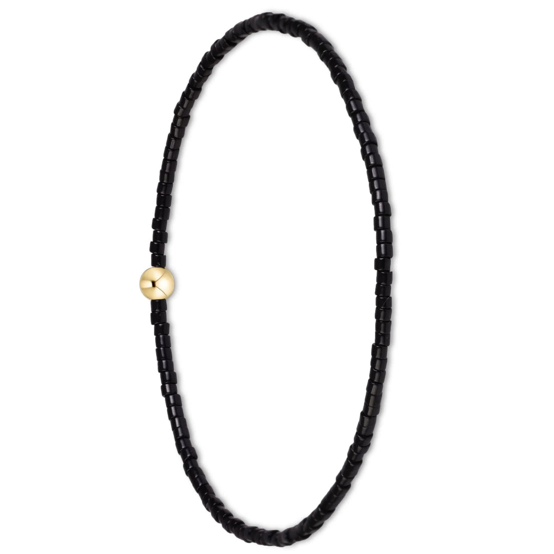 A beaded bracelet made of small black cylindrical beads with a single polished gold round bead at the clasp, shown on a plain white background.