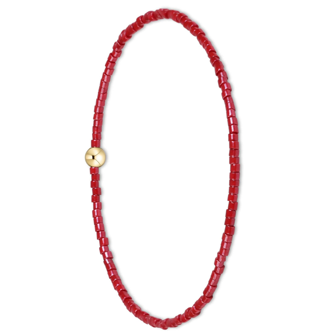 A beaded necklace made of small red cylindrical beads with a single round gold clasp, displayed on a clean white background.