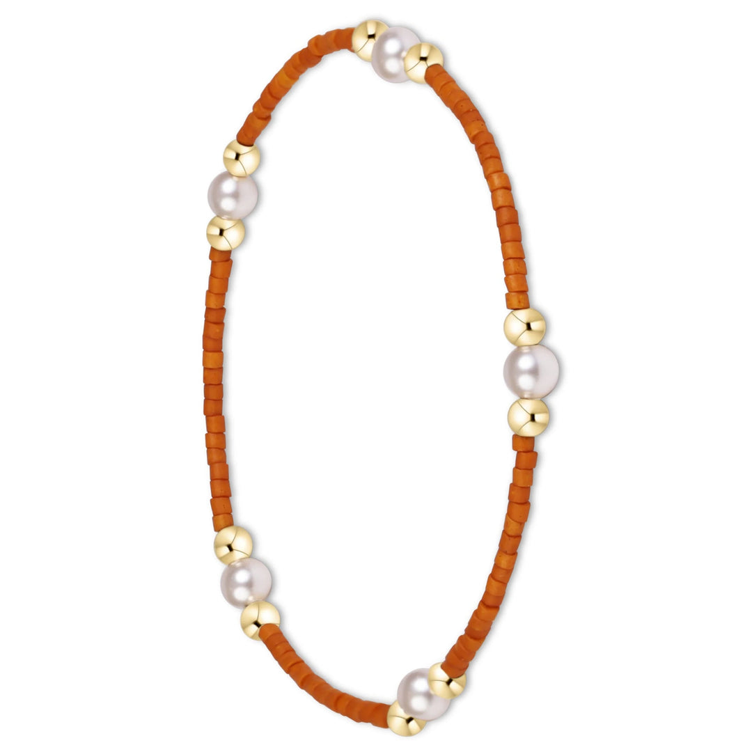 A delicate beaded bracelet featuring a warm orange-brown cord, small gold-toned beads, and three larger white pearls spaced evenly along the circle, set against a plain white background.