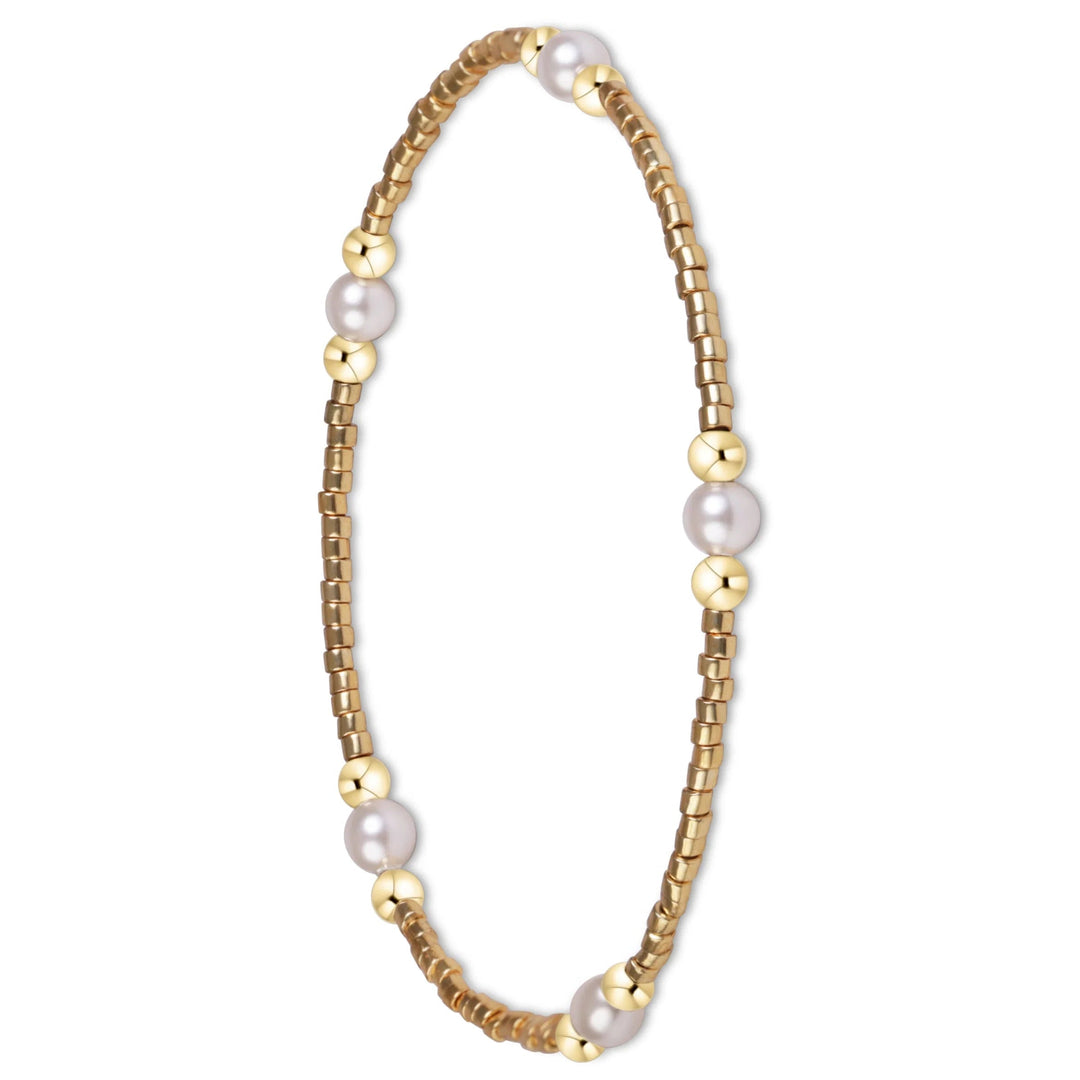 A delicate gold beaded bracelet with alternating small gold cube beads and larger smooth gold sphere beads, accented with five white freshwater pearls, shown on a plain white background.