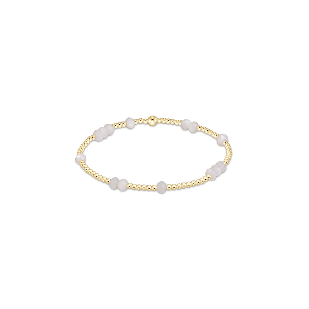 A delicate gold chain bracelet featuring alternating translucent white beads and small polished gold beads, displayed on a clean white background.