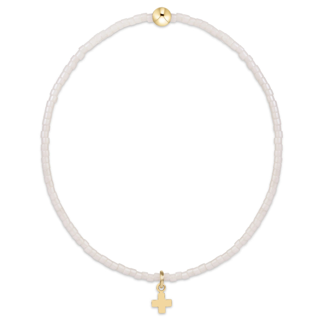 A delicate beaded necklace with small translucent white beads, featuring a small gold cross pendant and a gold accent bead at the top, shown on a plain white background.