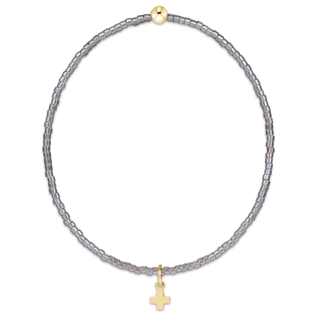A beaded necklace featuring small iridescent gray-blue beads and a small gold cross pendant, displayed on a clean white background.