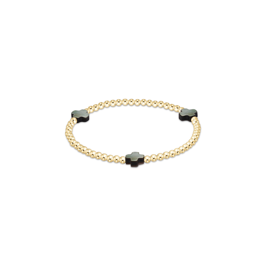 A gold beaded bracelet with three black clover-shaped beads, displayed on a clean white background.