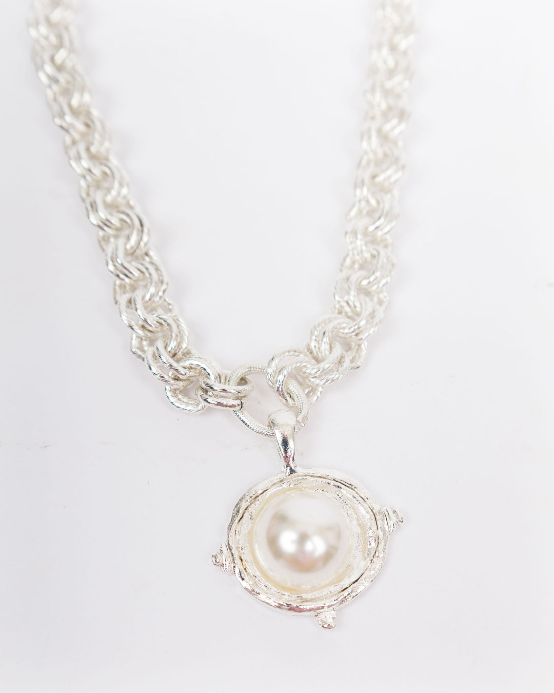 Silver necklace with a pearl pendant on a light gray background