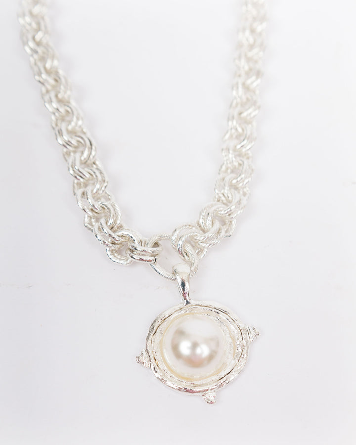 Silver necklace with a pearl pendant on a light gray background