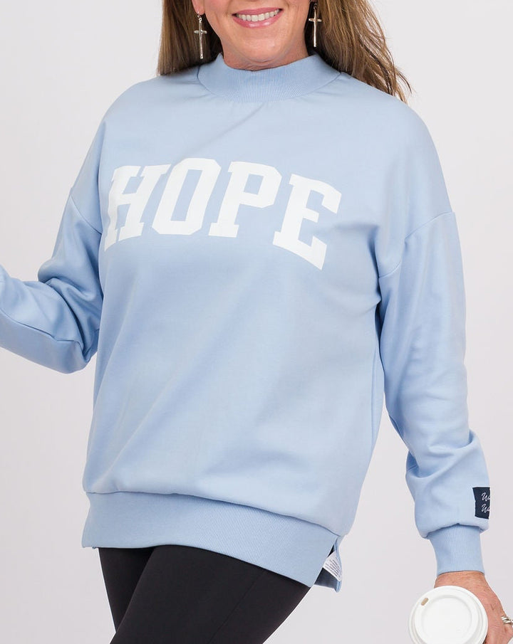 A woman modeling a light blue crewneck sweatshirt with &
