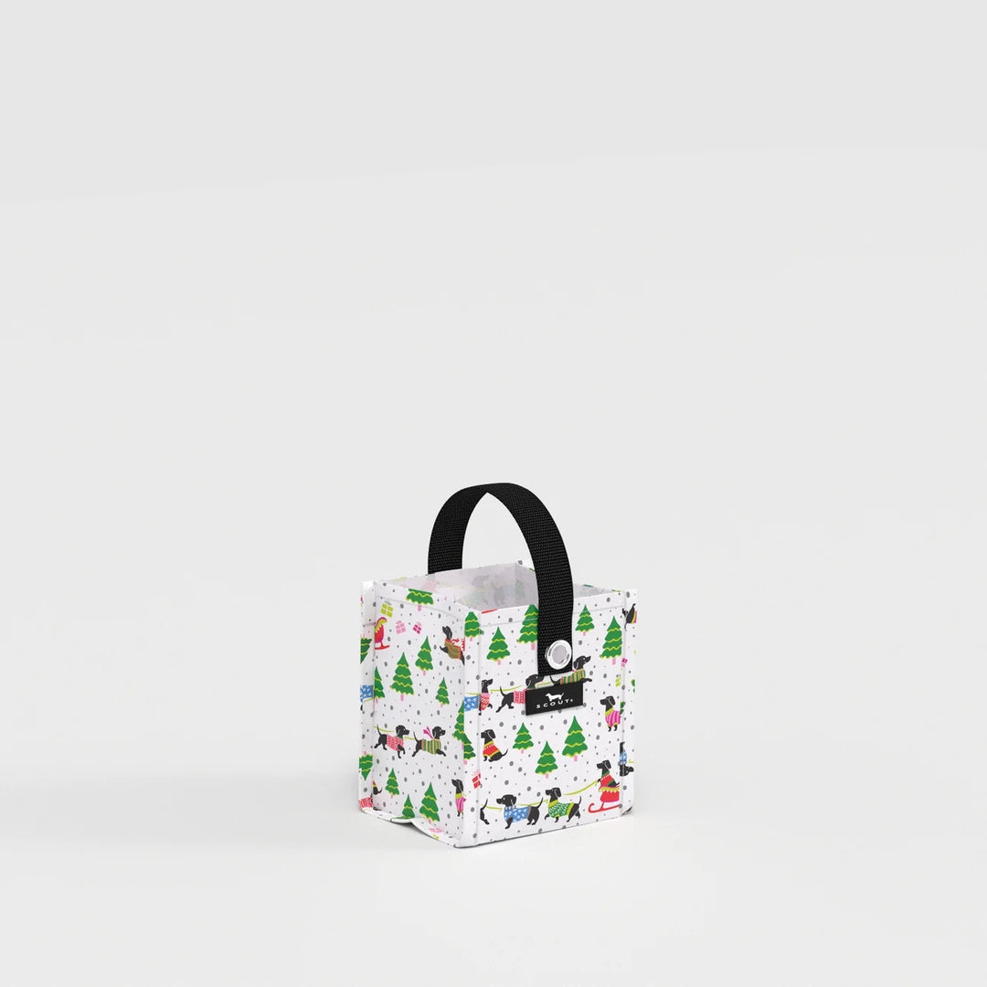 A small square tote bag with a black handle, featuring a white background covered in a colorful winter dog print with green Christmas trees, set against a clean white studio background.