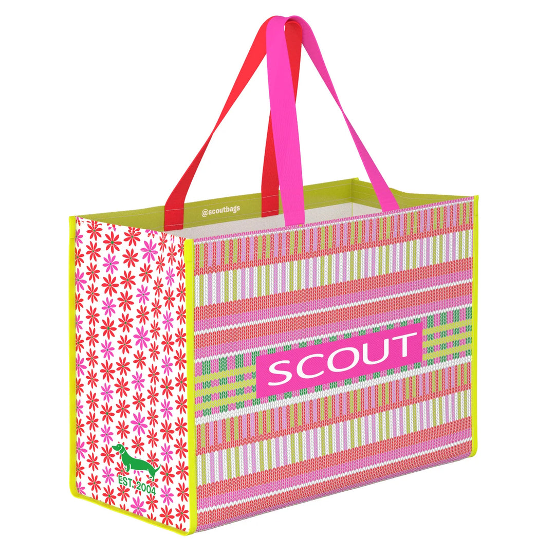 A reusable tote bag with a colorful striped and floral pattern, featuring bright pink handles and a pink &
