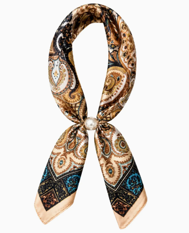 A silk scarf with an intricate paisley and geometric pattern in brown, beige, black, and blue, styled in a loop with a central pearl accent on a plain white background.