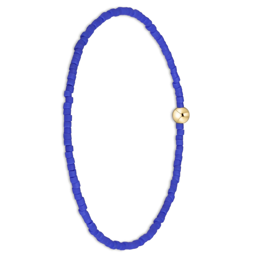 A beaded bracelet made of small, vibrant royal blue beads arranged in an oval shape, featuring a single polished gold-toned round bead at the top center, set against a plain white background.