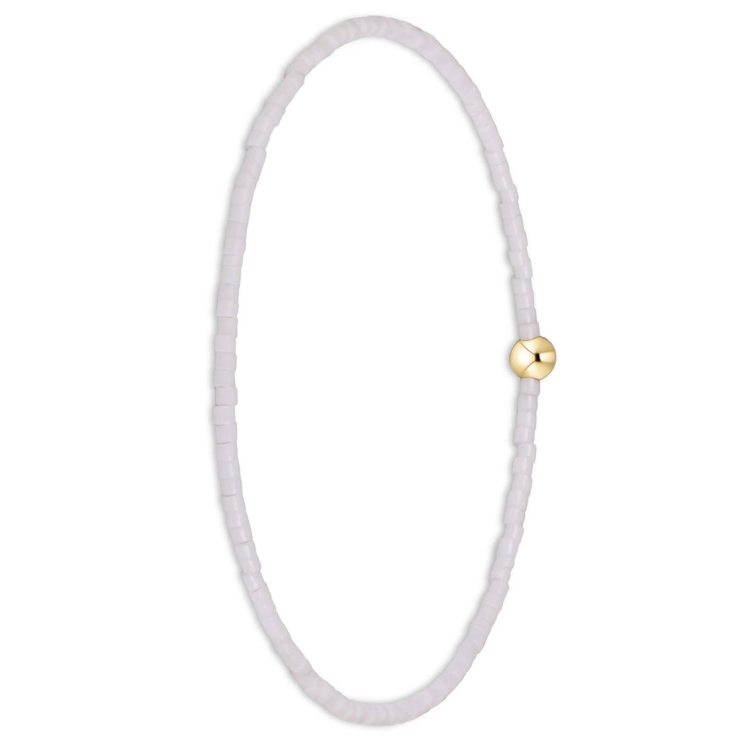 A delicate beaded bracelet with small, translucent pale lavender beads and a single polished gold clasp, shown on a clean white background.