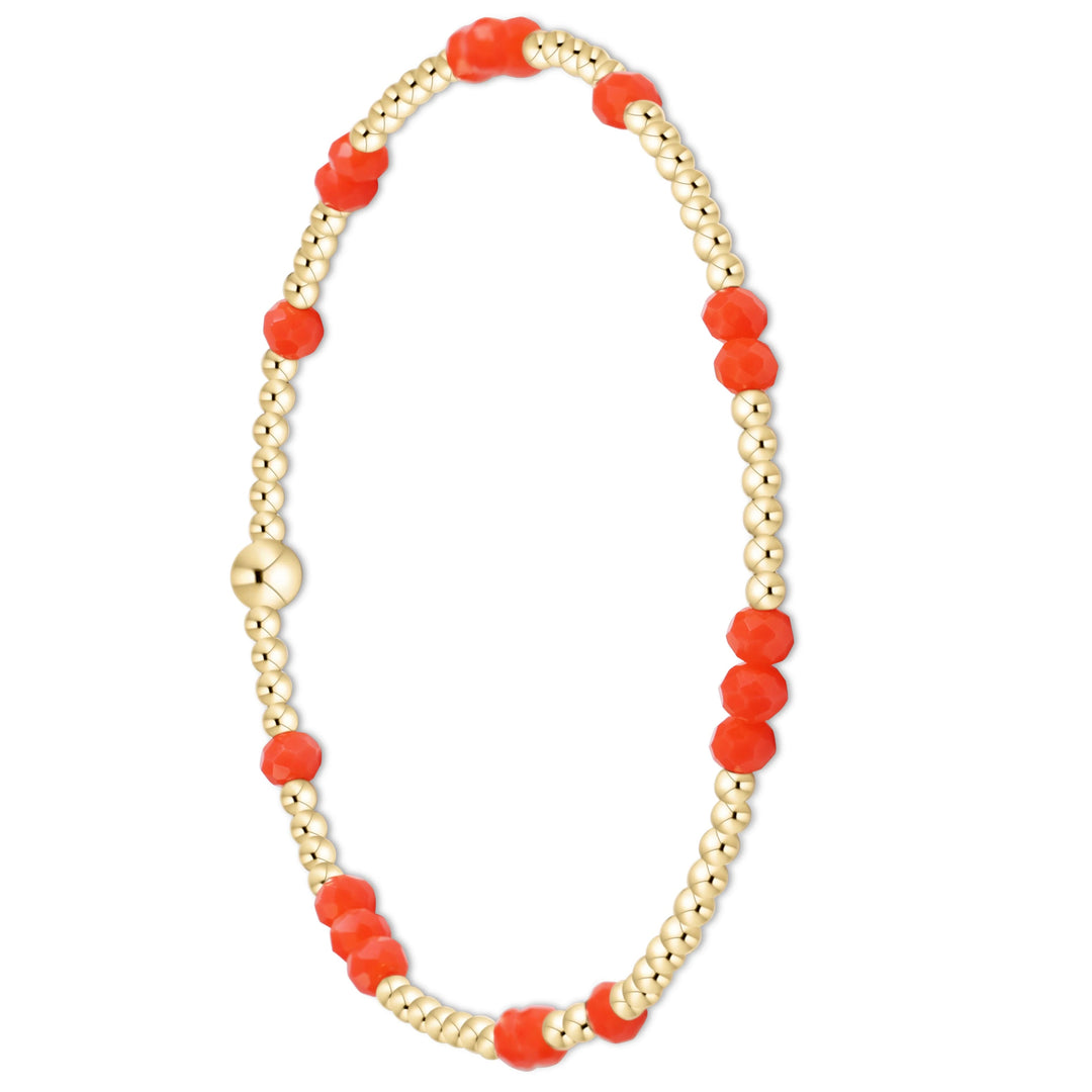 A delicate beaded bracelet featuring alternating strands of faceted orange-red beads and polished gold-toned round beads, completed with a matching gold clasp, shown on a plain white background.