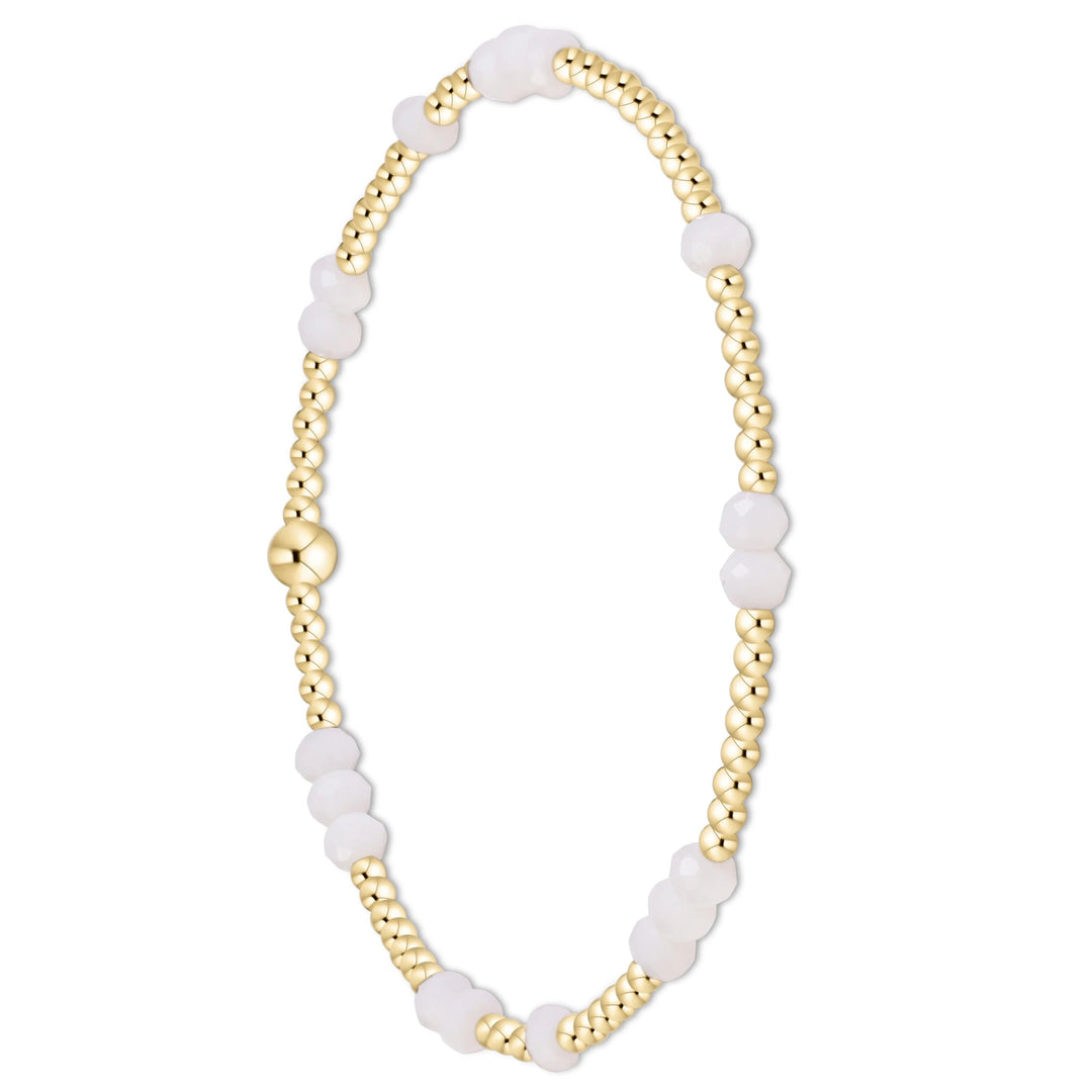 A delicate beaded bracelet featuring alternating sections of polished gold-toned beads and smooth, translucent white beads, completed with a round gold clasp, shown on a solid white background.