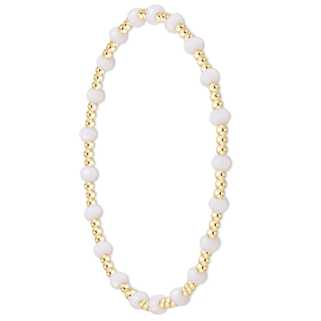 A beaded stretch bracelet featuring alternating matte white round beads and metallic gold textured beads, displayed on a clean white background.