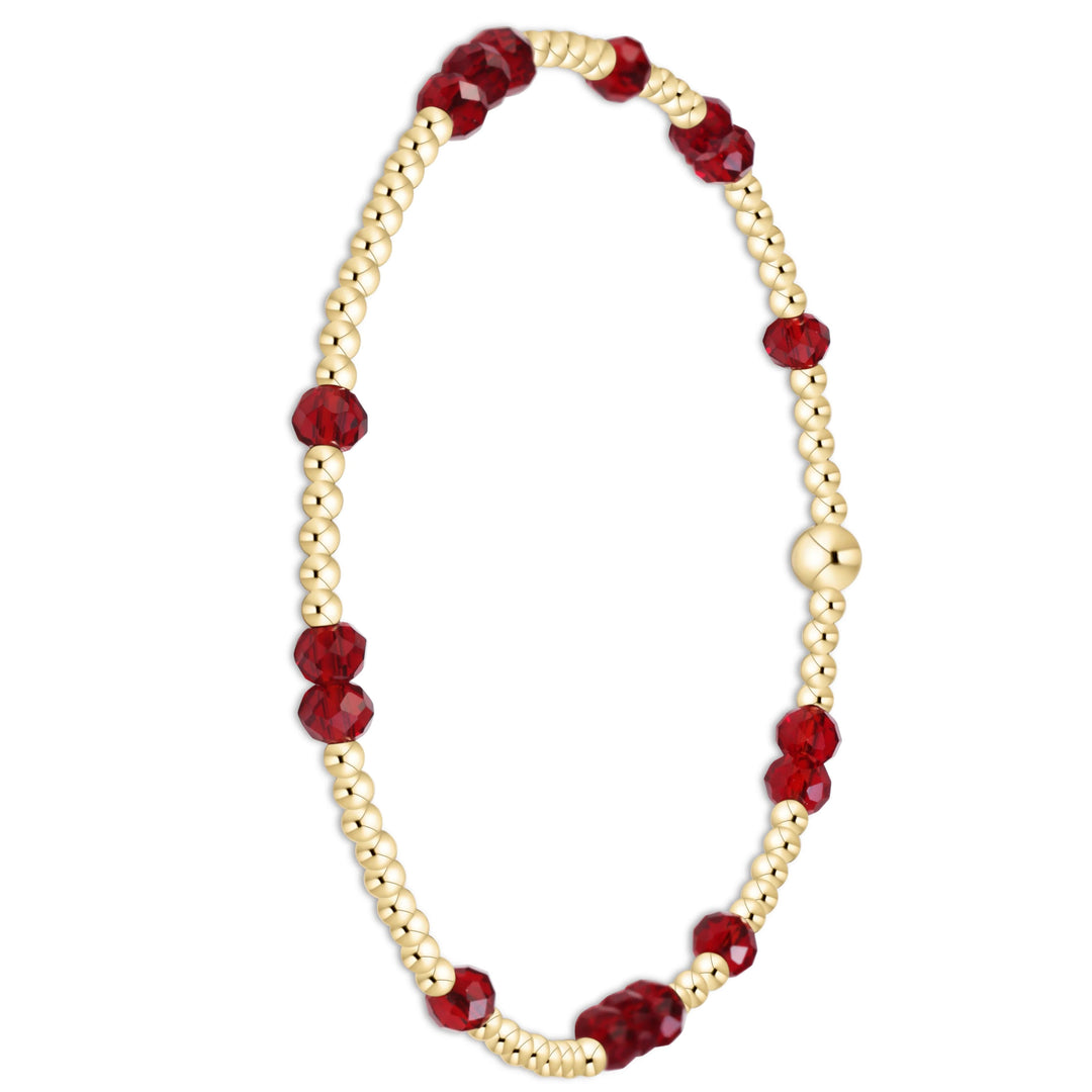 A beaded stretch bracelet featuring faceted deep red beads alternating with small metallic gold beads, completed with a polished gold clasp, shown on a solid white background.
