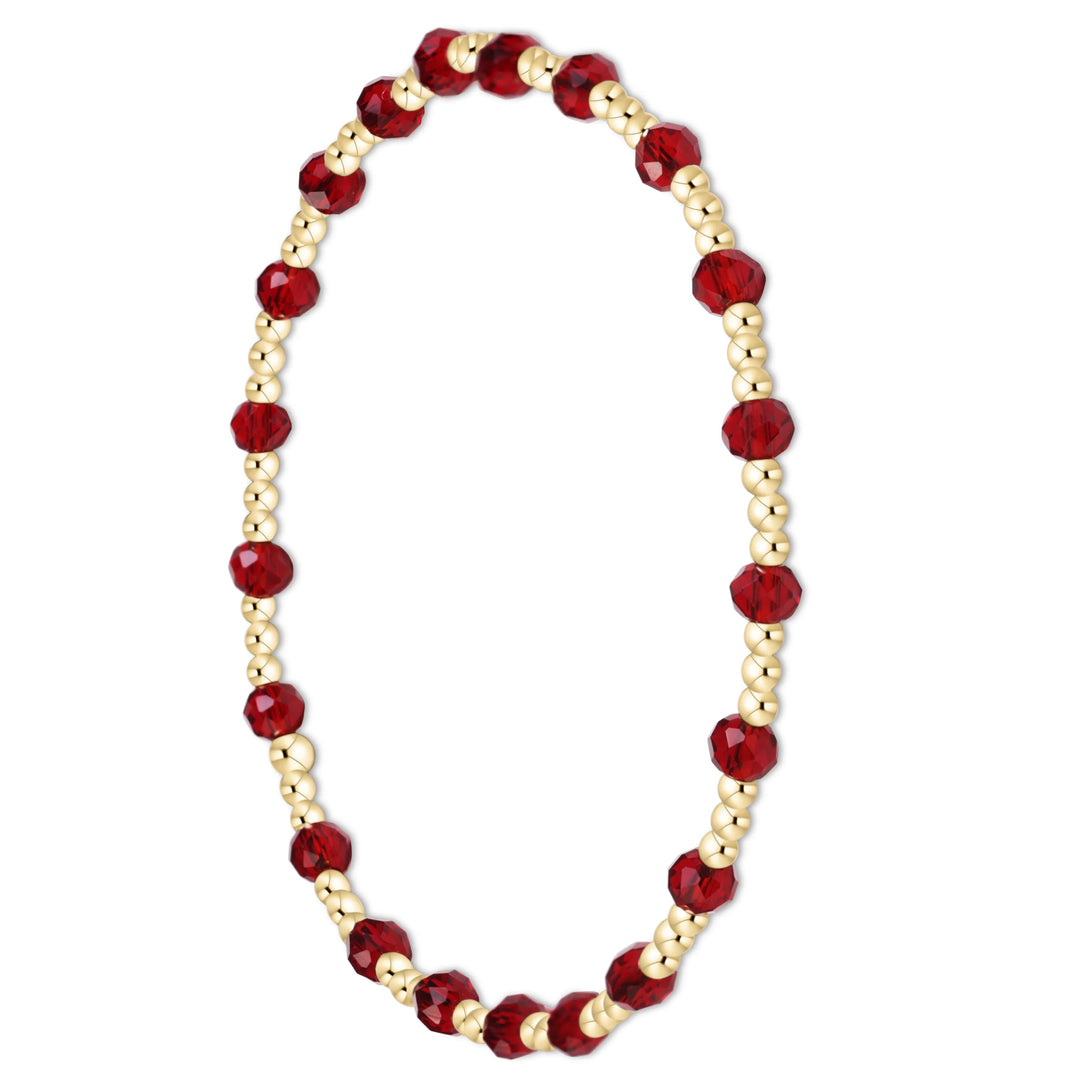 A beaded stretch bracelet featuring faceted deep red beads and small metallic gold beads, displayed on a clean white background.