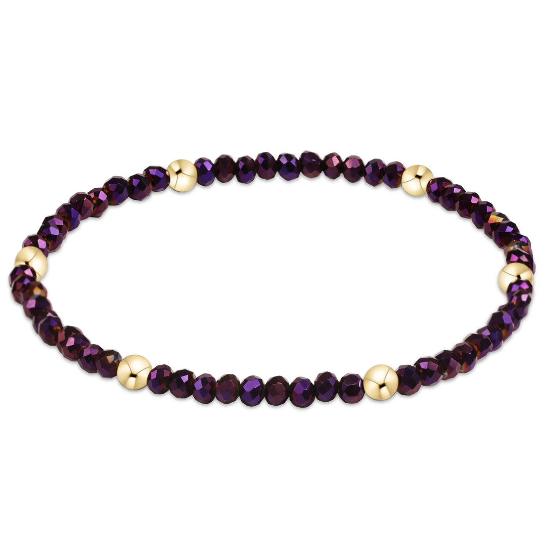 A beaded stretch bracelet featuring faceted dark purple beads and polished gold spacer beads, displayed on a clean white background.
