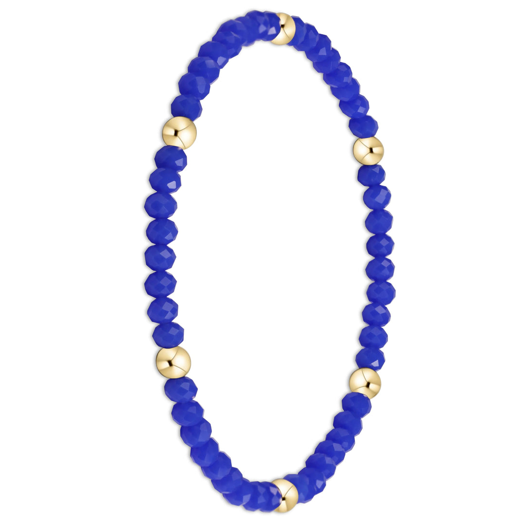 A beaded stretch bracelet featuring faceted royal blue beads and polished gold spacer beads, displayed on a clean white background.