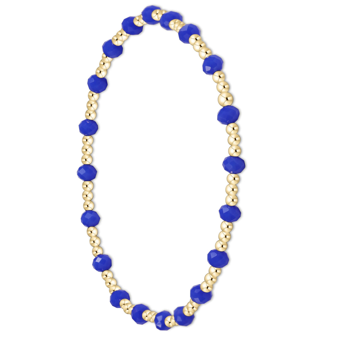 A beaded stretch bracelet featuring alternating royal blue faceted beads and gold-toned round beads, displayed on a clean white background.