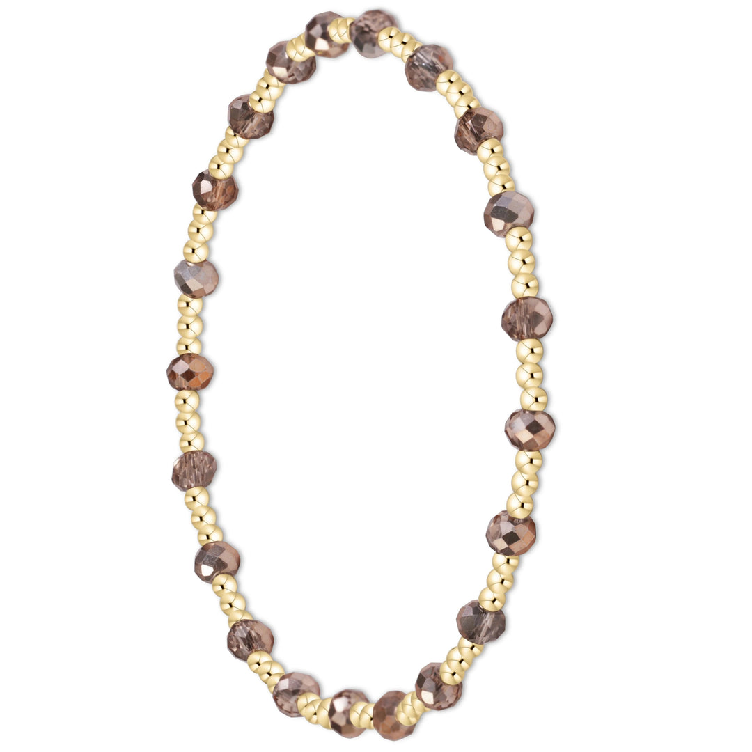 A beaded stretch bracelet featuring faceted brown smoky quartz beads and small gold metallic beads, arranged in a circular shape on a plain white background.