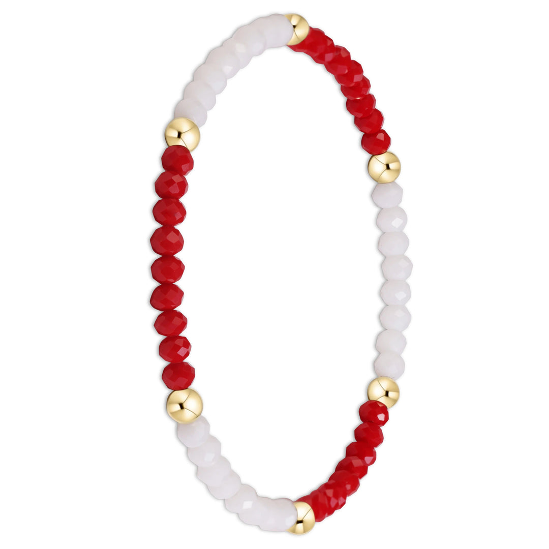 A beaded stretch bracelet featuring alternating sections of faceted red and milky white beads, accented by polished gold-tone round spacers, shown on a plain white background.