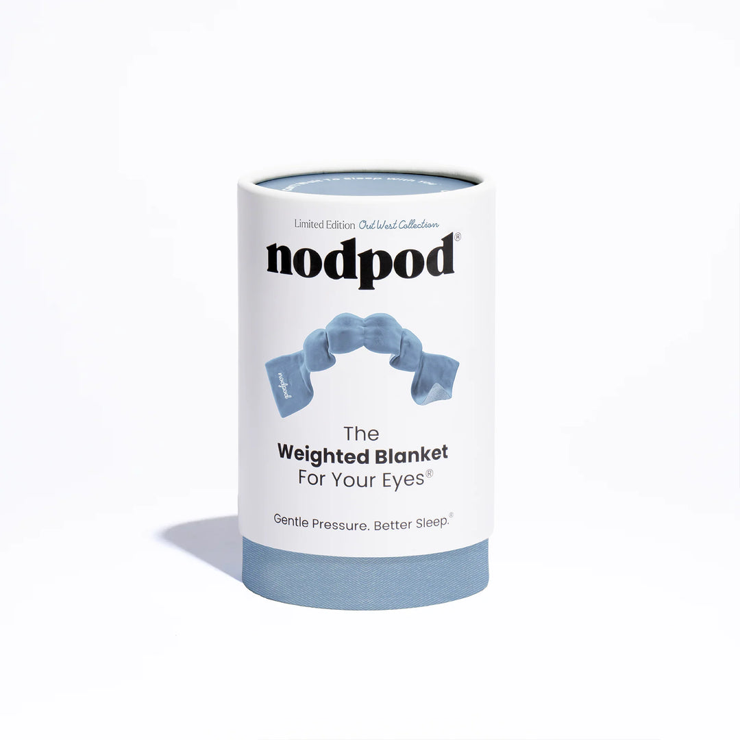 A cylindrical white product box for nodpod The Weighted Blanket For Your Eyes, featuring a light blue illustration of the weighted blanket and a solid light blue base, set against a clean white background.