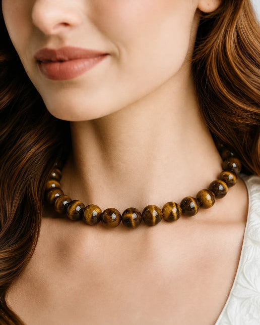 A close-up of a woman wearing a beaded necklace made of polished brown and gold tiger&