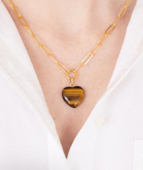 A gold chain necklace with an elongated paperclip-style link design and a heart-shaped pendant made of polished tiger&