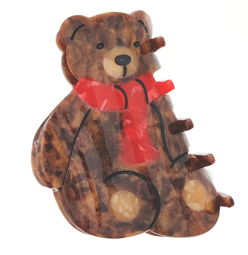 A teddy bear-shaped clutch or compact case made of marbled brown resin with a bright red scarf accent, shown against a plain white background.