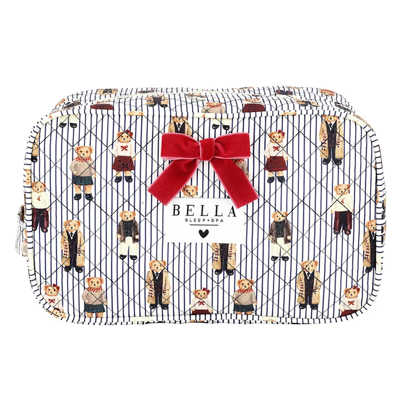 A zippered cosmetic pouch featuring a navy and white pinstripe background with a repeating pattern of teddy bears in school uniforms, accented by a large red velvet bow on the front and a white brand label that reads &