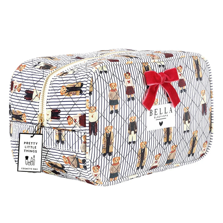 A quilted cosmetic pouch by Bella + Canvas featuring a navy and white pinstripe pattern with a repeating print of dogs in various outfits. The pouch has a gold zipper, a red bow, and a white brand tag.