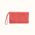 A coral pink leather wristlet clutch with a matching wrist strap, shown on a plain white background.