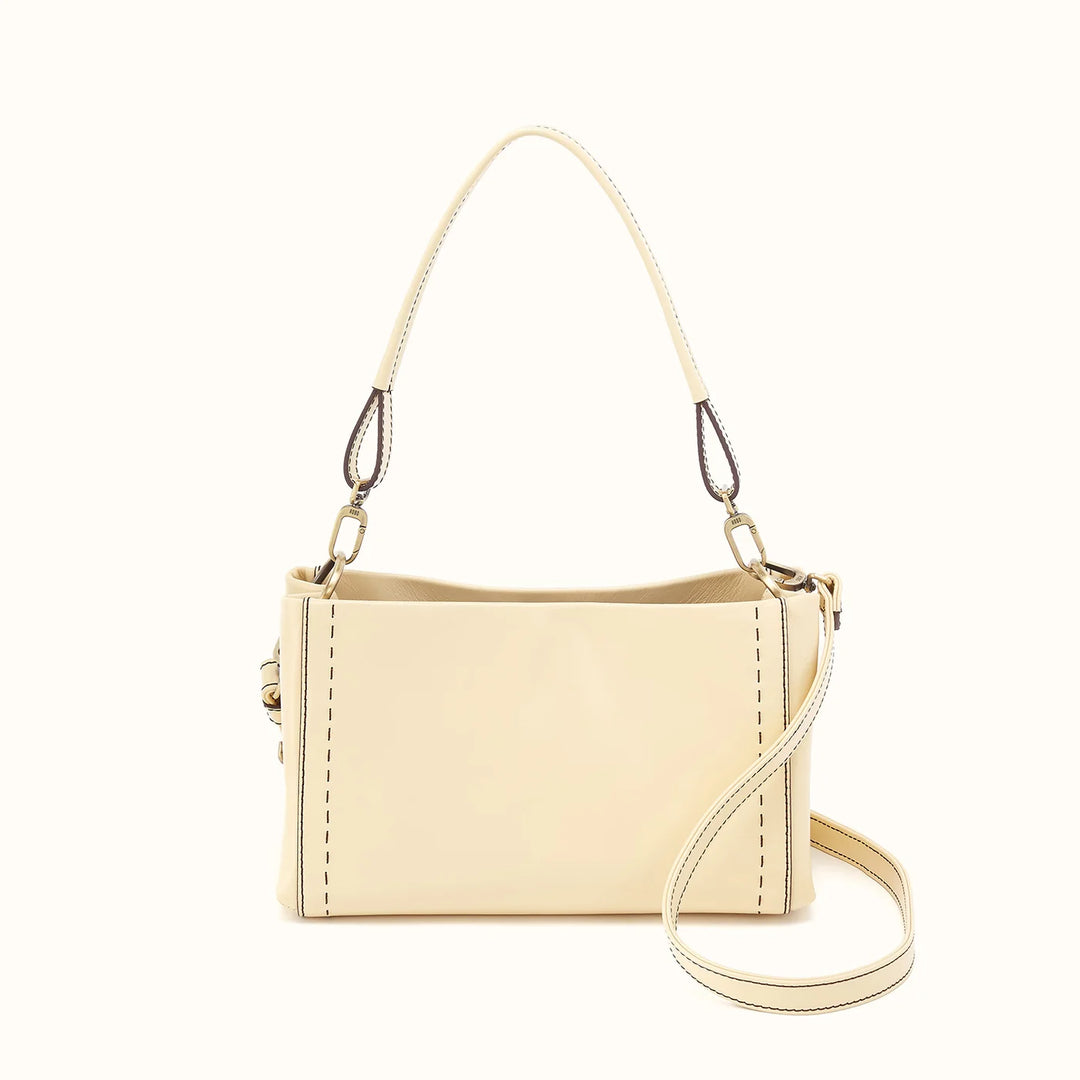A cream-colored faux leather shoulder bag with a top handle and a detachable shoulder strap, displayed on a solid off-white background.